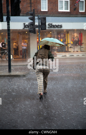 Frau in Heavy Rain und Regenschirm über König Straße in Twickenham - UK Stockfoto