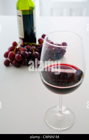 Stillleben: Glas Rotwein, Flasche und Weintraube. Stockfoto