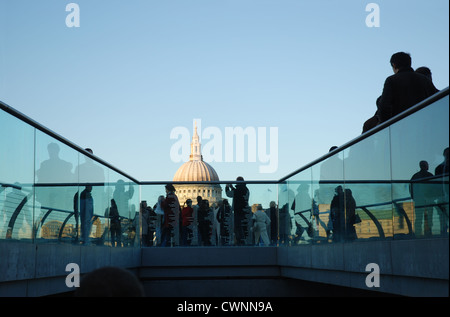 Massen von Pendlern, die Wogen über die Millennium Brücke; St. Pauls-Kathedrale im Hintergrund. London, England. Stockfoto
