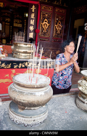 Fromme malaysischen chinesischen Frau in buddhistischen Tempel mit Händen gemeinsam beten und halten rauchen Räucherstäbchen in Malacca City. Stockfoto