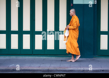 Thailändischen buddhistischen Mönch, der auf den Straßen von Bangkok am frühen Morgen tragen traditionelle Orange buddhistischen Roben und betteln um Almosen. Stockfoto