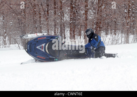 Schneemobil Reiter Spaß und drehen in frischen weißen Schnee. Scharfe Kurven Ergebnis in einem umgestürzten Schneemobil. Stockfoto