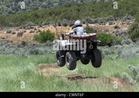 Motorrad ATV auf grobe Feldweg durch den Menschen. Sprünge über Rampen der Erde. Trägt einen Helm für Sicherheit. Stockfoto