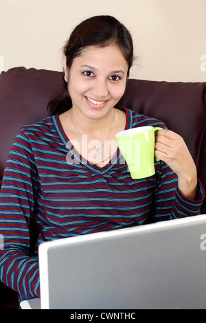 Glücklich Indianerin Kaffeetrinken während der Arbeit am laptop Stockfoto