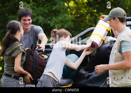 Junge Männer, um eine junge Dame laden Campingausrüstung auf Rückseite des Pick-up-truck Stockfoto