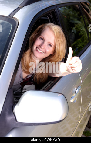 Lächelnde Mädchen im Auto mit Daumen Stockfoto