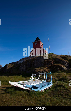 Hundeschlitten liegen in der Wiese vor der "neuen" Kirche Sisimiut, die zweitgrößte Stadt in Grönland im Jahr 1926 erbaut. Stockfoto