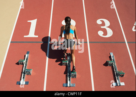 Sportlerin in Startposition auf Laufstrecke, Rückansicht Stockfoto