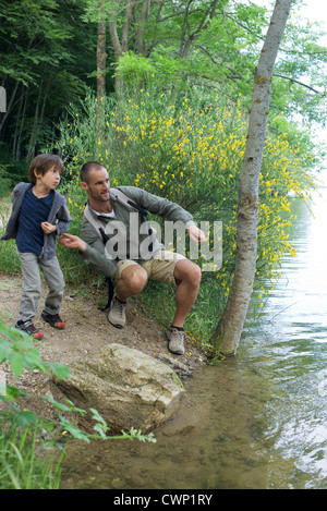 Vater und Sohn werfen Kieselsteine in Fluss Stockfoto