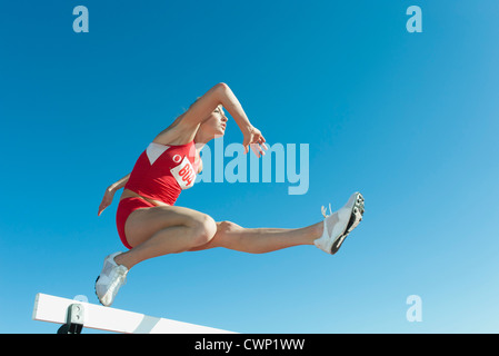 Famale Athleten springen über die Hürde, niedrigen Winkel Ansicht Stockfoto