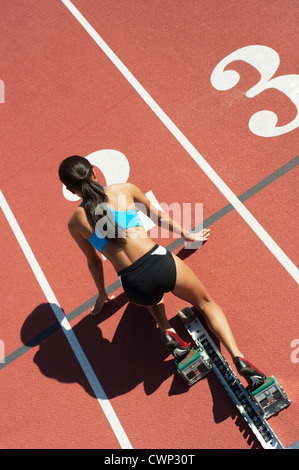 Sportlerin in Startposition auf Laufstrecke, Rückansicht Stockfoto