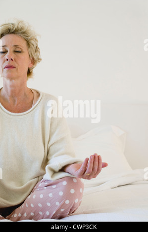 Reife Frau, meditieren auf Bett, beschnitten Stockfoto