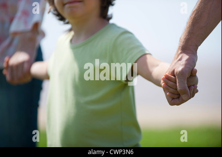 Junge, die Hand in Hand mit Eltern, beschnitten Stockfoto