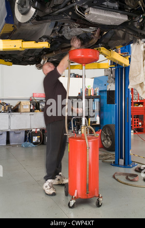 Kfz-Mechaniker in einer Garage Werkstatt Ölwechsel im Getriebe arbeiten. Stockfoto