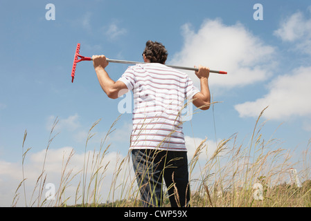 Mann, stehend im Rasen mit Hausanteil auf Schultern, Rückansicht Stockfoto
