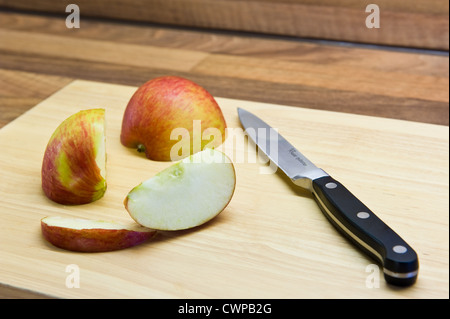 Teilweise geschnittenen Apfel, auf einem Küchenbrett mit einem Messer. Stockfoto