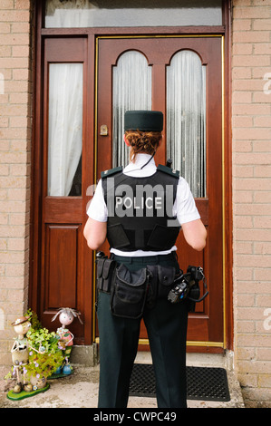Polizistin wartet vor der Tür eines Hauses Stockfoto