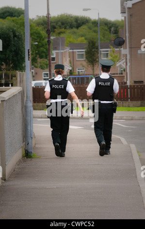 Weibliche und männliche Polizisten zu Fuß auf dem Gehweg einer Straße in einem Wohngebiet (Vignettierten) Stockfoto