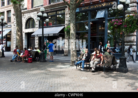 unterschiedliche Gruppen von Menschen entspannen Sie auf Bänken oder ein Spaziergang in der Sonne Schecken Pioneer Square historische Zentrum von Seattle Stockfoto