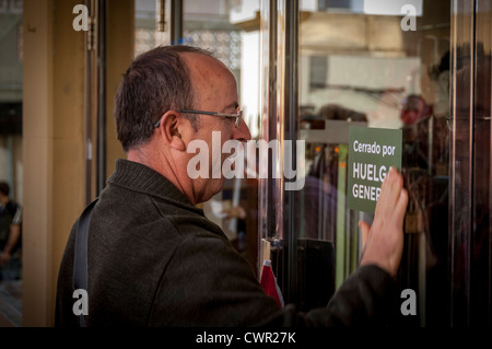 Ein Demonstrant legt einen Aufkleber auf einer Ladentür in Benidorm während des Generalstreiks in Spanien am 29. März 2012. Stockfoto