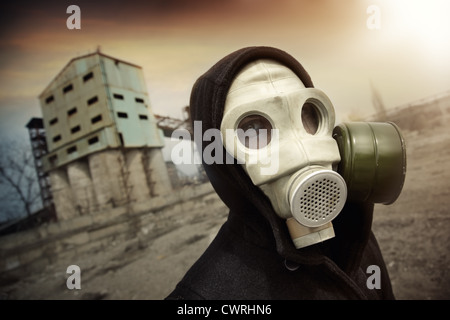 Mann in schützende Gasmaske in der Nähe der Industrieanlage bei radioaktiven Sonnenuntergang. Künstlerisch Farben und Korn hinzugefügt Stockfoto