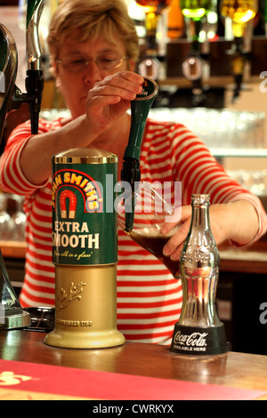 Eine Bardame Gießen einen Pint bitter Stockfoto