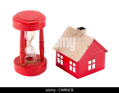 Rotes Haus Nachahmung und gebrochenen Sand Glas Uhr isoliert auf weißem Hintergrund. Immobilienblase zusammenbrechen. Stockfoto