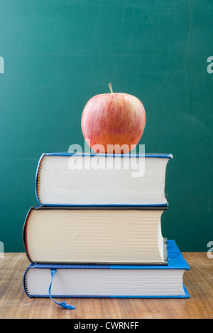 Verstaubte Schulbücher auf dem Schreibtisch. Auf der Oberseite einen Apfel und Platz für Text und Grafiken. Stockfoto