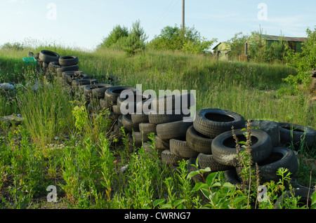 Zaun aus der alten gebrauchten Reifen auf Wiese. Natürliche Verschmutzung. Stockfoto