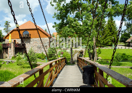 Rostige Ketten halten Brücke im Park und Gebäudewand aus Steinen gemacht. Stockfoto