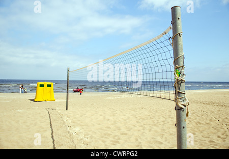 Volleyballnetz auf Meeressand vergeuden bin und Leute in der Nähe von Bademeister Motorboot. Stockfoto