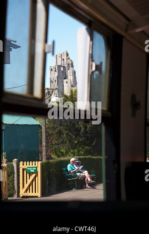 Blick durch ein Fenster mit Dampfzug der Burg und paar saß auf der Bank am Corfe Castle Station im Mai Stockfoto