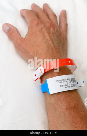 Einen Mann auf einem Krankenhausbett mit Identifikation Armbänder Stockfoto