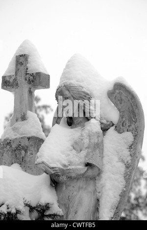 schwerer Stein Engelsstatue mit Schnee bedeckt Stockfoto