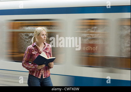 Junge Frau Buch vor u-Bahn vorbei Stockfoto