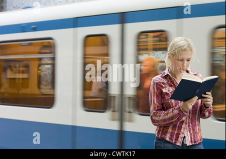 Junge Frau Buch vor u-Bahn vorbei Stockfoto