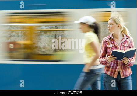 Junge Frau Buch vor u-Bahn vorbei Stockfoto