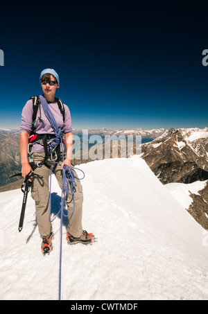 Ein Bergsteiger auf dem Gipfel des Weissmies (4017m) mit Fletschhorn in der Ferne stehen. Stockfoto