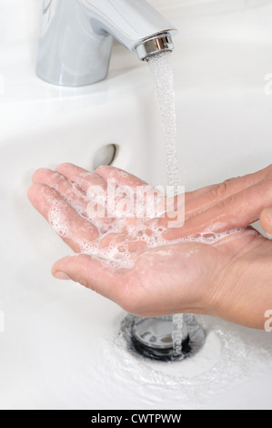 Waschen Sie ihre Hände mit Seife in Waschtisch Waschbecken Wasserhahn Einseifen Frau Stockfoto