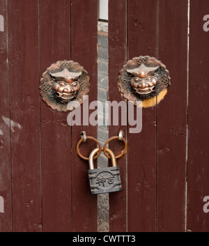 Zwei chinesische Löwenköpfe schmücken eine alte verschlossene Tür in der Stadt Nanjing in China. Stockfoto