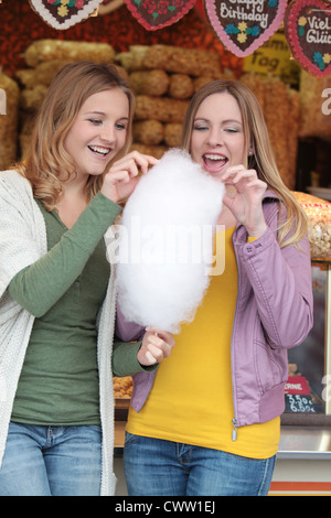 Zwei glückliche Frauen auf einer Kirmes essen Zuckerwatte Stockfoto