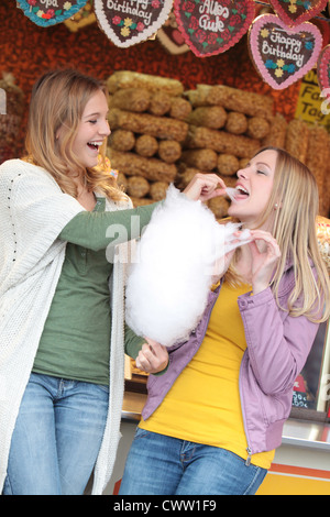 Zwei glückliche Frauen auf einer Kirmes essen Zuckerwatte Stockfoto