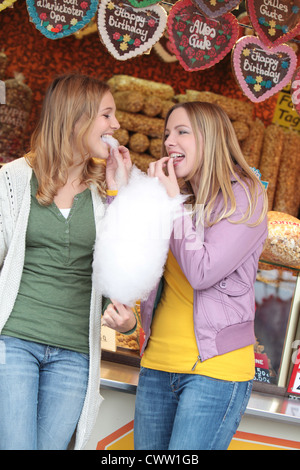 Zwei glückliche Frauen auf einer Kirmes essen Zuckerwatte Stockfoto