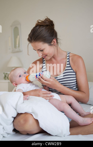 Lächelnde Mutter mit der Flasche füttern baby Stockfoto