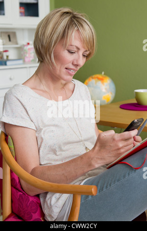 Frau mit Handy in Küche Stockfoto