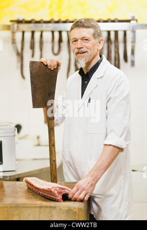 Metzger holding großes Messer und Fleisch Stockfoto