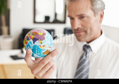 Geschäftsmann Miniatur Globus holding Stockfoto