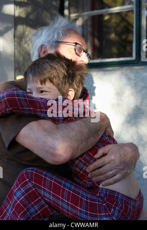 Ältere Mann umarmt Enkel im freien Stockfoto