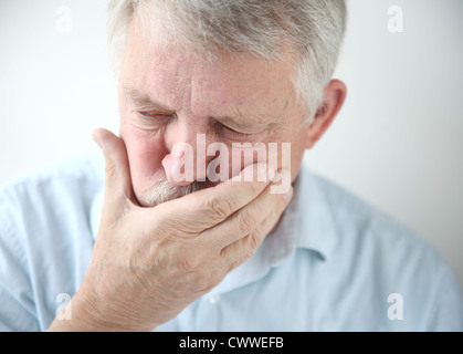 ältere Mann hält seine Hand zum Mund während das Gefühl der Übelkeit Stockfoto