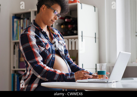 Schwangere Frau mit Laptop in der Küche Stockfoto